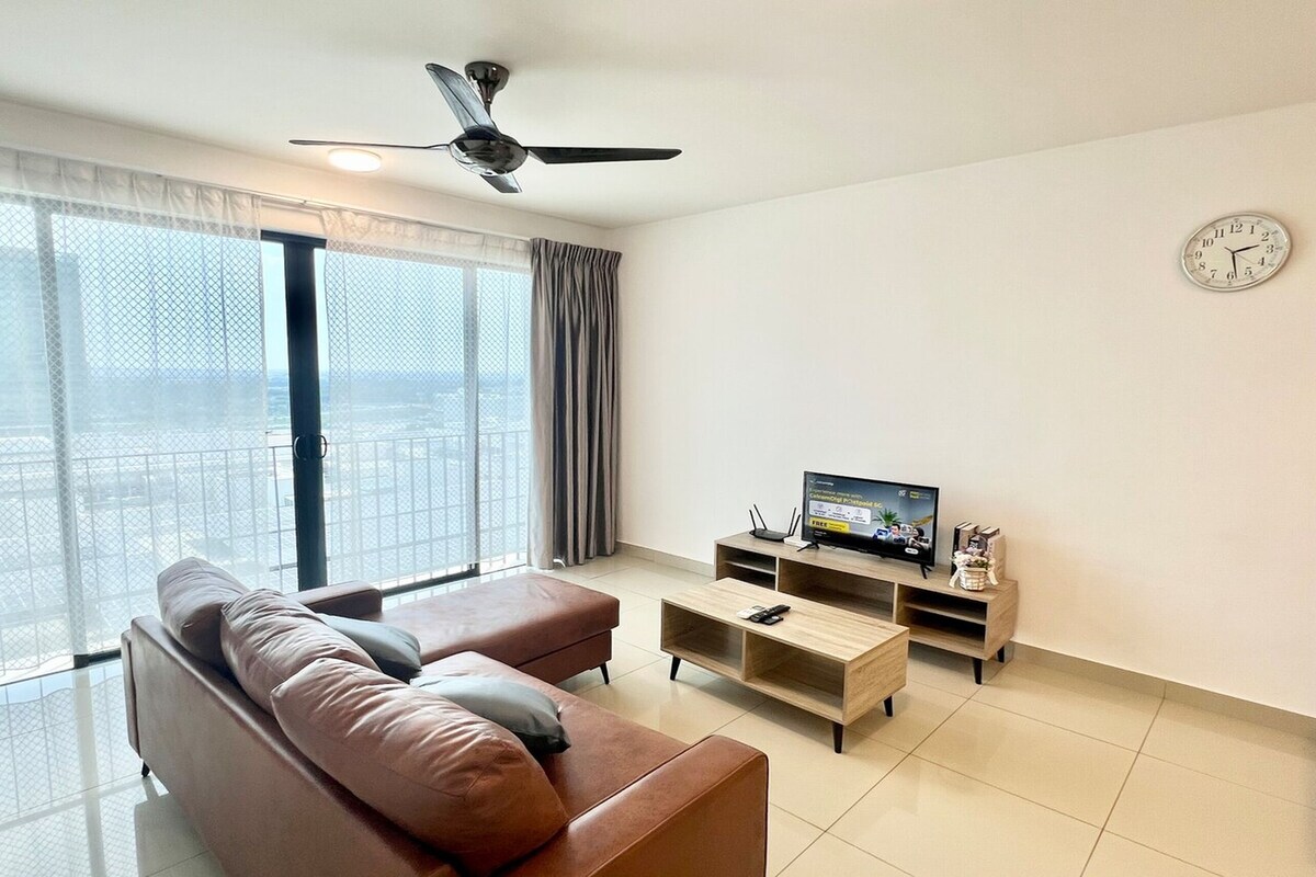 Een moderne woonkamer met een bruine leren bank, een televisie op een houten dressoir en een plafondventilator.