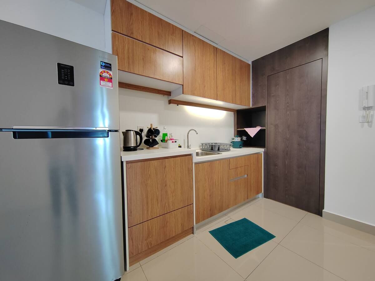 Een moderne keuken met houten kastjes, een roestvrijstalen koelkast, een spoelbak en een teal vloerkleed.