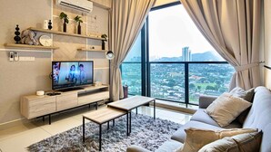 Un salon moderne avec un téléviseur, un canapé et une grande fenêtre donnant sur la ville.