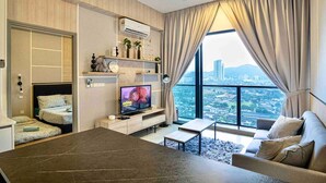 Une chambre d’hôtel moderne équipée d’un lit, d’une télévision, d’un canapé et d’une grande fenêtre donnant sur la ville.