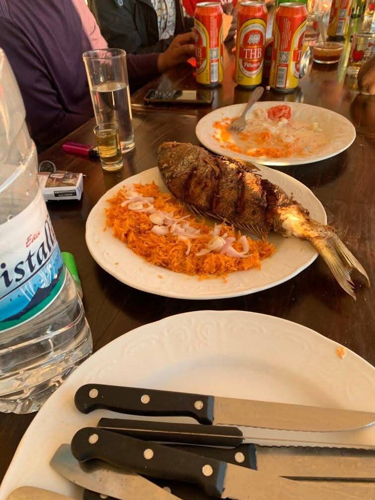 A dining table with plates of food, a bottle of water, and a knife.