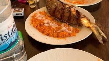 Una mesa de comedor con platos de comida, una botella de agua y un cuchillo.