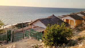 A coastal village with traditional thatched-roof houses, a sandy beach, and a clear view of the sea. - Hotel Mira d'Or amboaboaky toliara (Toliara)
