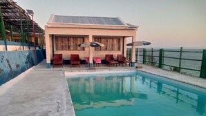 A pool area with a building, lounge chairs, and umbrellas. - Hotel Mira d'Or amboaboaky toliara (Toliara)