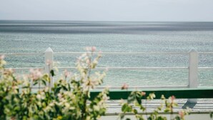 A view of the sea from a wooden deck with white railings, framed by blooming flowers. - Hotel Mira d'Or amboaboaky toliara (Toliara)