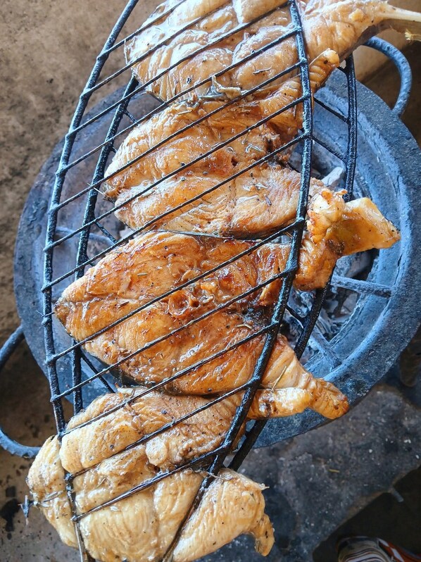 Una parrilla con varios trozos de pollo cocinándose.