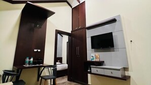 Ein Hotelzimmer mit einem Bett, einem Schreibtisch mit Stuhl, einem an der Wand befestigten Fernseher und einem Kleiderschrank.