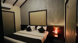 Ein Schlafzimmer mit schrägen Wänden, einem Bett mit Kopfteil, Nachttischen und einer Wandleuchte.
