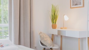 A room with a desk, chair, lamp, potted plant, and a framed picture on the wall. - Rentaflat Norderstedt 2BR Apartment for 4 Guests (Norderstedt)