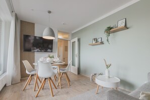 Et moderne spiseområde med et rundt bord, hvide stole og en hængende lampe.