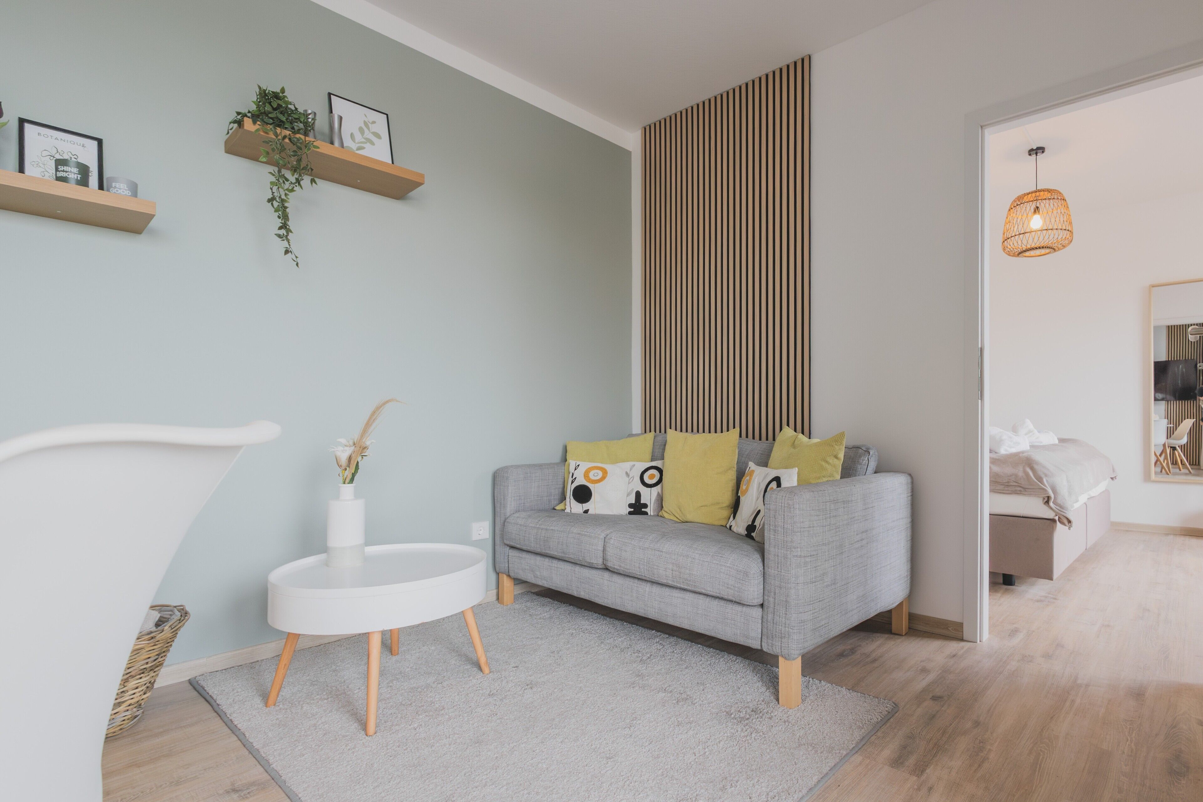 Un salon moderne avec un canapé gris, une petite table d’appoint blanche et un petit tapis blanc.