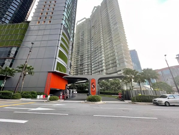 A modern urban street with high-rise buildings, a prominent orange structure, and a clear road with directional arrows.