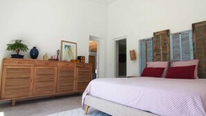 Un dormitorio con cama, armario de madera y objetos decorativos.