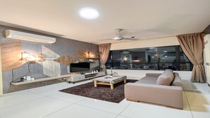 A modern living room with a flat-screen TV, a sofa, a coffee table, and a large window with a city view. - Kajang MKH Boulevard Apartments (Kajang)