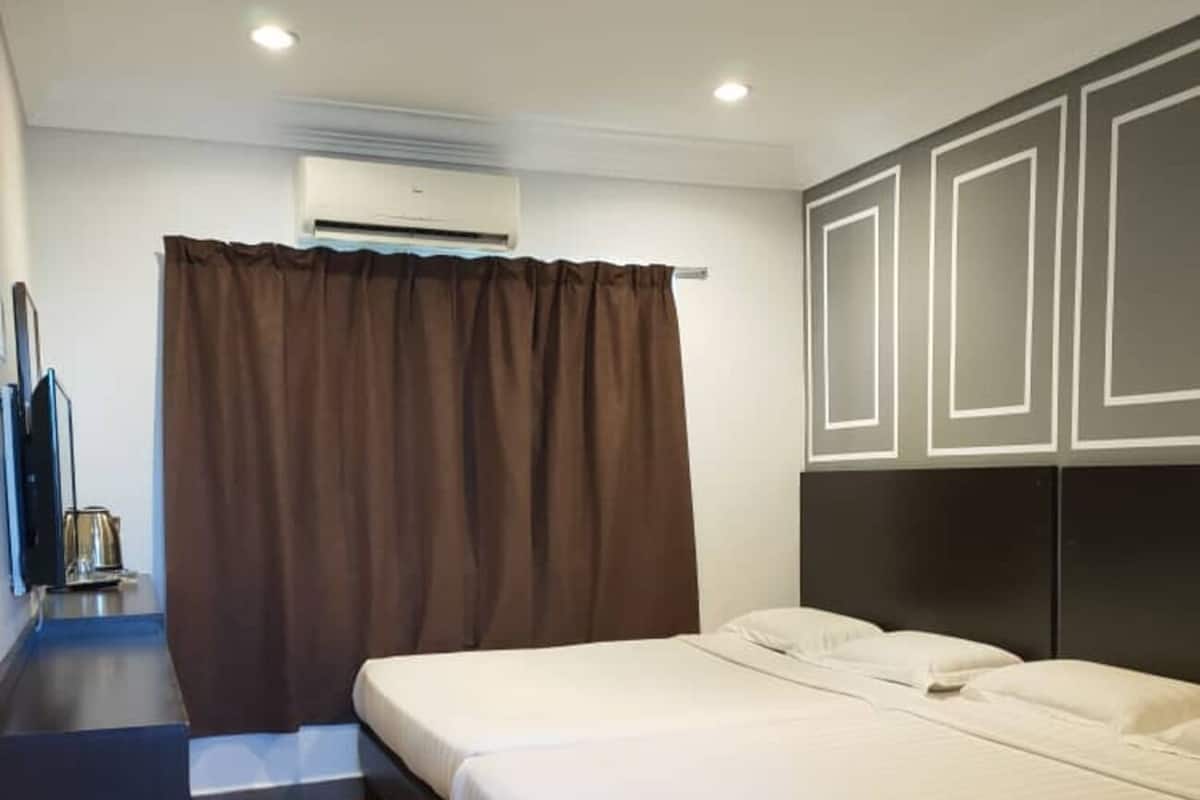 A hotel room with a bed, a desk, and an air conditioning unit.