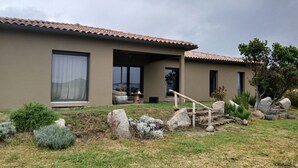 A modern house with a flat roof, large windows, and a well-maintained garden with rocks and shrubs. - New villa T4 Sotta between land and sea (Sotta)