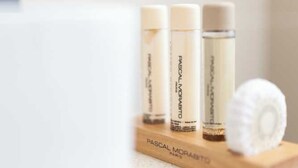 Three bottles of Pascal Morabito skincare products on a wooden tray. - Hotel Tinah: Elegance and Comfort Near the Champs-elysees (Paris)