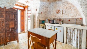 Cozinha rústica com parede de pedra, móveis de madeira, máquina de lavar e micro-ondas.