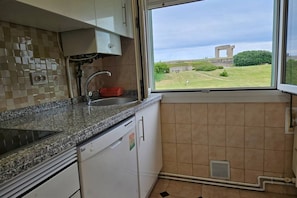 A kitchen with a window view of a grassy area and a structure.