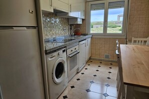 Una cocina con lavadora, lavamanos y ventana con vistas.