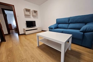 A living room with a blue sofa, a white TV stand, and a white coffee table.
