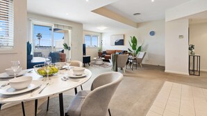 A modern living room with a dining area, featuring a round table set for four, a sofa, and a coffee table.