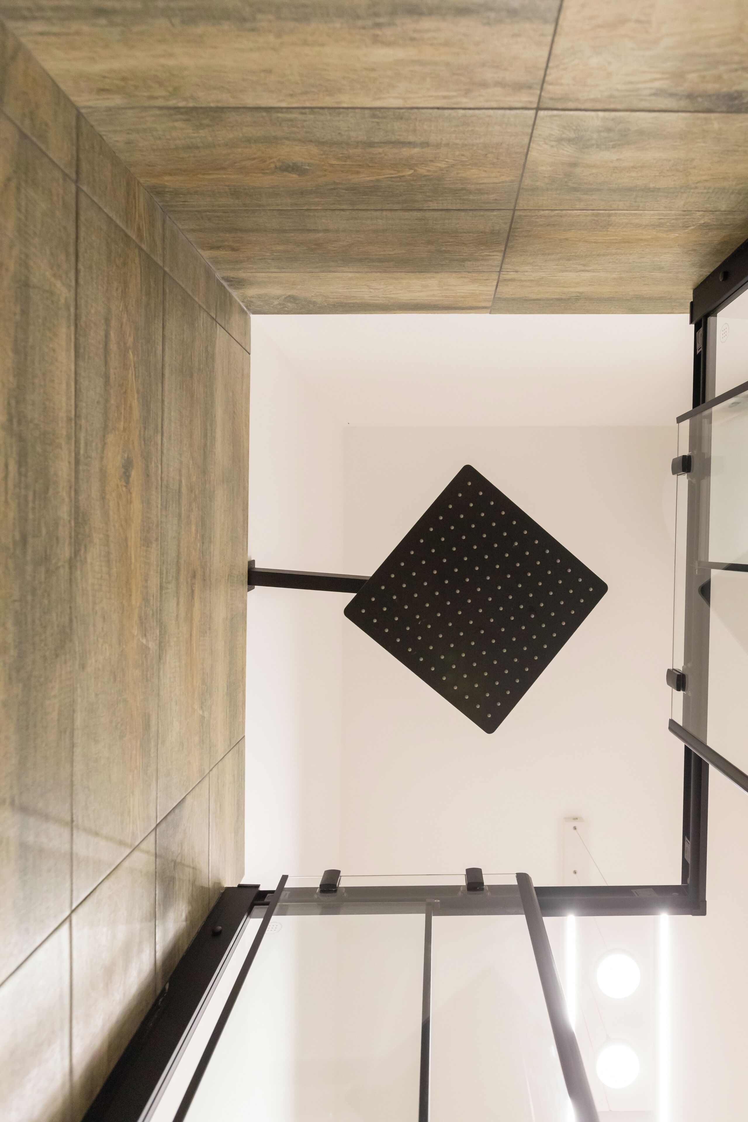 Un intérieur moderne avec un plafond en bois, une œuvre d’art murale géométrique noire et une cloison en verre.