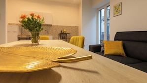 A modern living room with a dining table, a sofa, and a vase of flowers. - Aromarìa Palace  (Palermo)