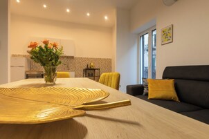 Una sala de estar moderna con una mesa de comedor, un sofá y un jarrón de flores.