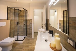 A modern bathroom with a glass-enclosed shower, a white sink with candles, and a large mirror. - Aromarìa Palace  (Palermo)