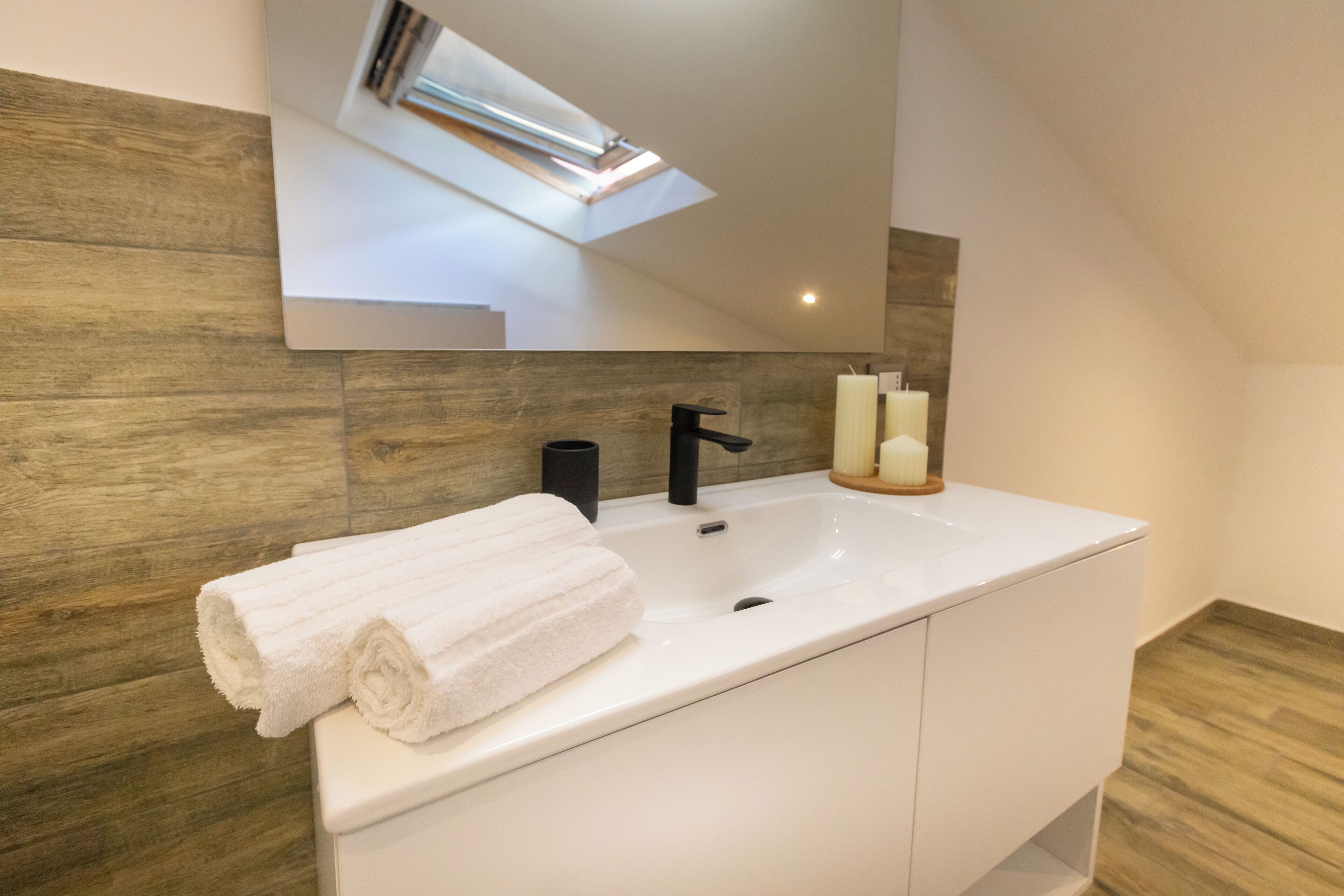 Un baño moderno con un lavabo blanco, un grifo negro y una toalla sobre la encimera.