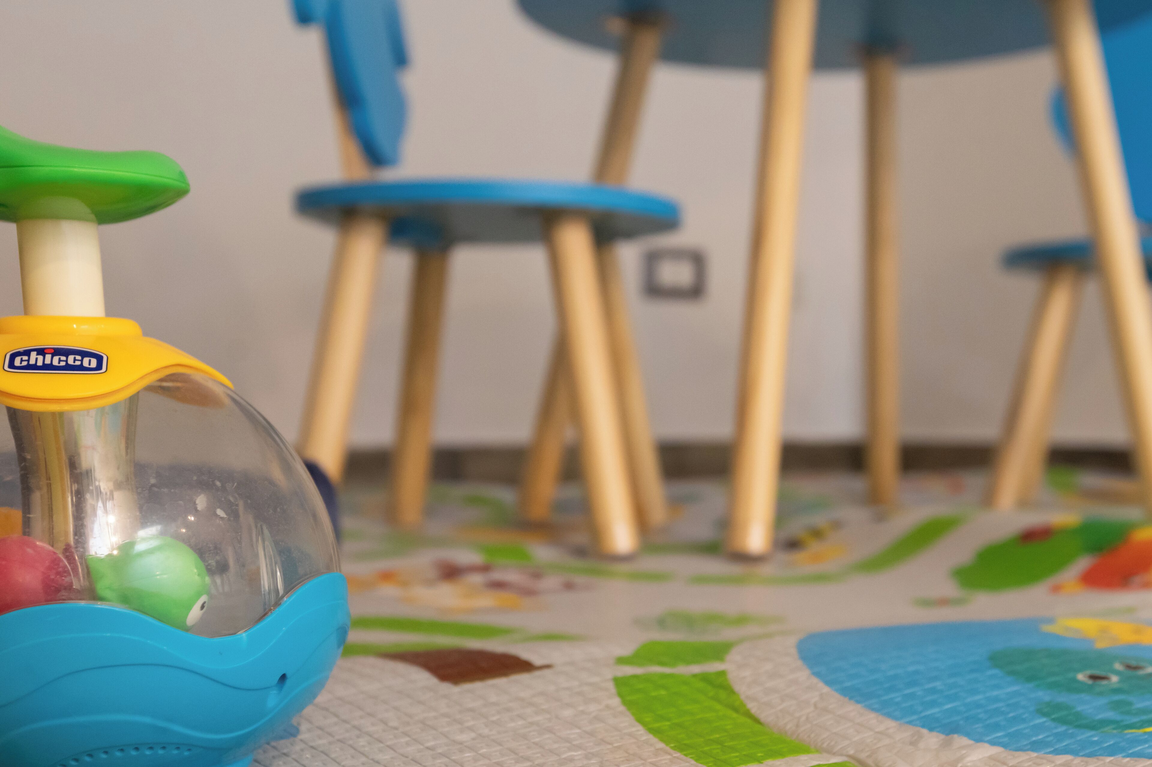 Un jouet pour enfant aux couleurs jaune et bleu, doté d’un dôme transparent et d’une poignée verte.