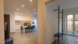 A modern kitchen with white cabinets, a dining area with a wooden table and chairs, and a balcony with a metal railing. - Aromarìa Palace  (Palermo)