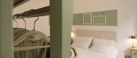 A hotel room with a bed, a nightstand, and a wall-mounted air conditioning unit.