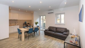 A modern living space with a dining area, a brown leather sofa, and a glass coffee table with decorative items. - Aromarìa Palace  (Palermo)