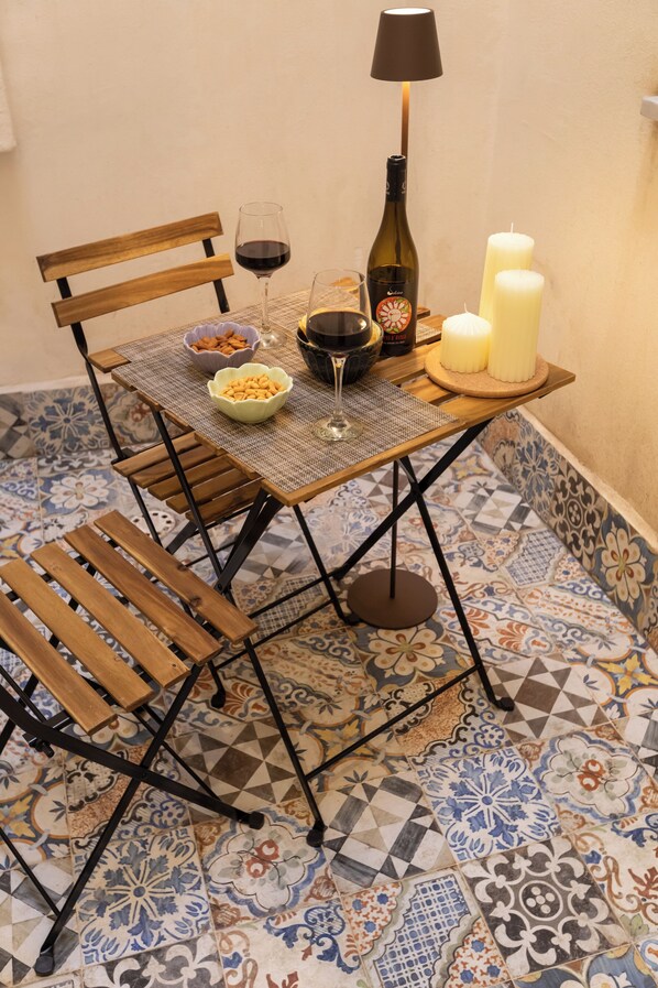 A dining table with a bottle of wine, glasses, candles, and a bowl of snacks. - Aromarìa Palace  (Palermo)