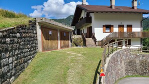 A stone wall, a grassy area, a building with a balcony, and a staircase. - Apartment 'Pozzobon' with Mountain View, Shared Garden and Wi-Fi (Caracoi Agoin)