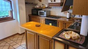 A kitchen with wooden cabinets, a microwave, a stove, and a sink. - Apartment 'Pozzobon' with Mountain View, Shared Garden and Wi-Fi (Caracoi Agoin)