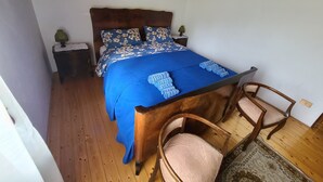 A bedroom with a wooden bed frame, a blue bedspread, two bedside tables with lamps, and two wooden chairs. - Apartment 'Pozzobon' with Mountain View, Shared Garden and Wi-Fi (Caracoi Agoin)