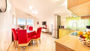 A modern kitchen with a dining area, a refrigerator, and a fruit bowl on the counter. - A6 apartment with terrace and the sea view, 4 min walk to the beach (Podstrana)