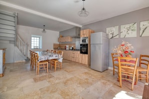 Una cocina amplia con comedor, armarios de madera, un refrigerador y una escalera.