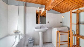 A bathroom with a bathtub, a sink, a toilet, and a wooden ladder.