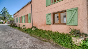 A building with green shutters, a gravel driveway, and a garden area. - Gîte le lilas - Farm Cottage "la capelle" (La Cassaigne)