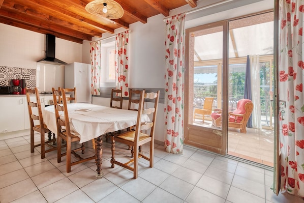 A dining area with a table and chairs, a kitchen with a stove and refrigerator, and a sliding glass door leading to an outdoor seating area.