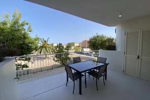 A balcony with a table and chairs, overlooking a street with palm trees and buildings. - Playa de Puzol con terraza y piscina (Puçol)