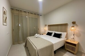 Ein ordentlich eingerichtetes Schlafzimmer mit Bett, Nachttischlampen, einem Nachttisch und einem Fenster mit Vorhängen.