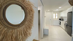 Une cuisine moderne avec des meubles blancs, un réfrigérateur noir et un four à micro-ondes.