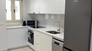 Une cuisine moderne avec des meubles blancs, un réfrigérateur en acier inoxydable, un four à micro-ondes et un lave-vaisselle.