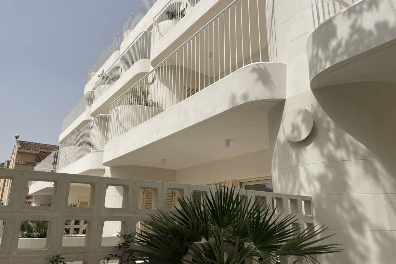 Un bâtiment moderne doté de nombreux balcons, d’une façade incurvée et d’une palette de couleurs dominée par le blanc.