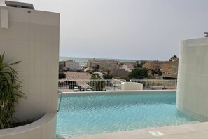 A swimming pool with a view of the sea and buildings in the background. - Playa de Puzol con terraza y piscina (Puçol)